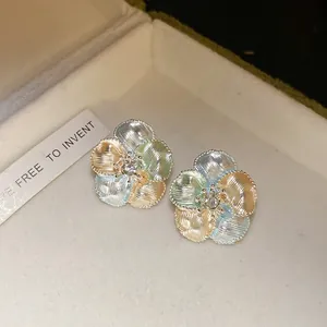 Dettaglio macro di orecchini a lobo a fiore con petali in smalto e zircone centrale