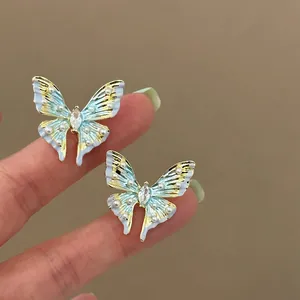 Detailed view of light blue enamel butterfly stud earrings with pearls and crystal