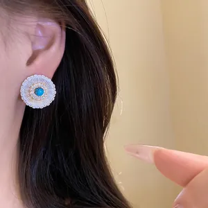 Close-up of vintage sunburst stud earring with turquoise center stone and zircons.