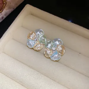 Dettaglio squisito di orecchini a lobo a fiore multicolore con zircone in un vassoio.
