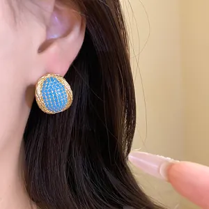 Close-up of vintage oval stud earrings with blue mosaic center on model's ear