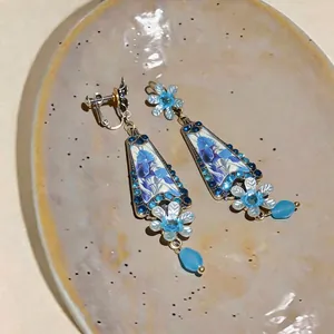 Close-up of vintage crystal flower glass pendant earrings displayed on a ceramic plate