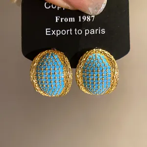 Close-up of vintage oval gold-toned earrings with blue turquoise textured center