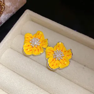 Vista dettagliata di orecchini a lobo a fiore giallo con zirconi e piccole perle