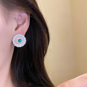 Detailed view of a vintage round zircon stud earring with a blue center stone on an ear