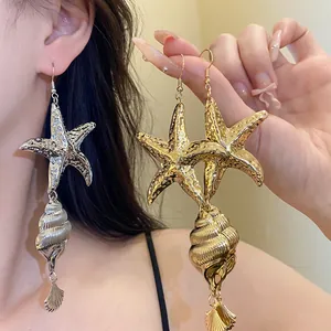Close-up detail of retro metallic gold and silver starfish and conch shell statement earrings.