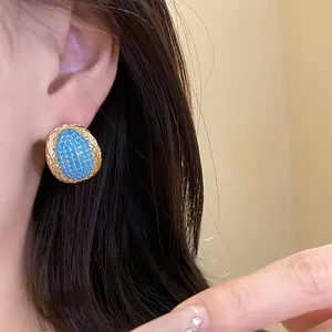 Detail shot of vintage oval stud earring with blue zircon stones and golden rope border