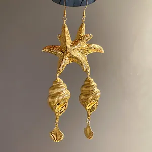 Close-up of vintage gold metallic earrings featuring starfish and seashell dangles