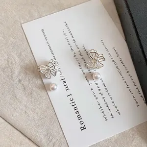 Close-up of silver butterfly stud earrings with elegant white pearls and rhinestones
