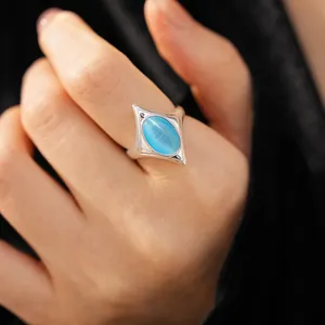 Detailed macro view of silver open ring featuring an oval blue cat-eye stone in star frame.
