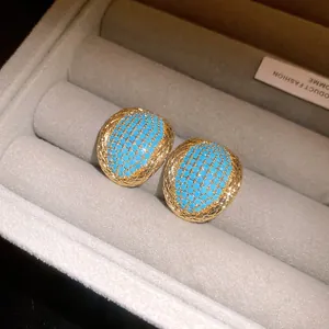 Detailed view of vintage gold-tone oval earrings with blue turquoise beads in a box