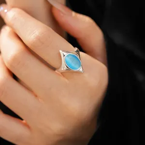 Macro detail of elegant silver star-shaped ring featuring an oval blue cat's eye stone