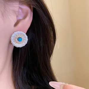 Close-up of vintage sunburst earrings with turquoise center and zircon details