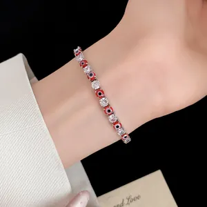 Close-up detail of a silver-toned tennis bracelet featuring red evil eyes and clear CZ