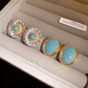 Detail view of vintage turquoise earrings and floral studs in a velvet jewelry box.