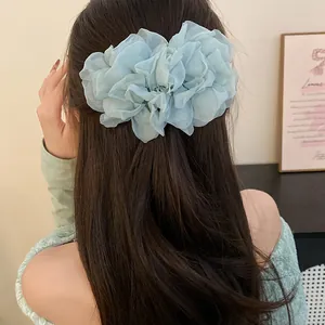 Dettaglio di un fermaglio per capelli a fiore in chiffon azzurro su capelli castani.
