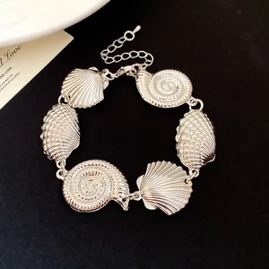 Macro detail view of a vintage silver-colored seashell and conch link bracelet jewelry