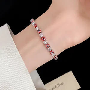 Detailed view of a red evil eye bracelet with sparkling cubic zirconia on a wrist.