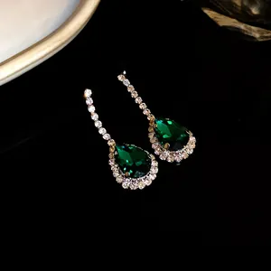 Dettaglio di orecchini a goccia verde smeraldo con brillante alone di cristalli