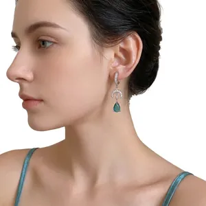 Elegant silver moon and teal teardrop dangle earrings with zircon pavé worn by a model