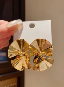 Detailed macro view of gold-plated pleated round stud earrings with glossy metallic finish