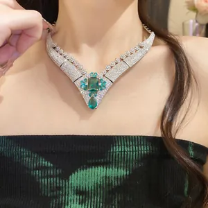 Detailed close-up of a vintage emerald green V-shaped necklace with zircon stones