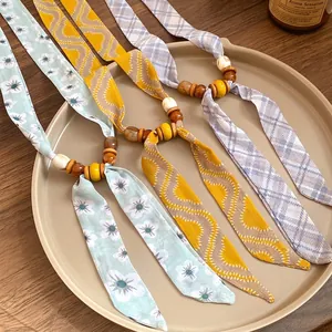 Handmade colorful beaded fabric necklaces with floral and plaid patterns on beige tray