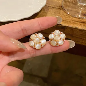 Κοντινό πλάνο με λεπτά σκουλαρίκια λουλούδια με επιχρύσωση 18 καρατίων και ζιργκόν.