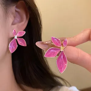 Elegant pink oil-drop flower stud earrings worn on ear and held by hand