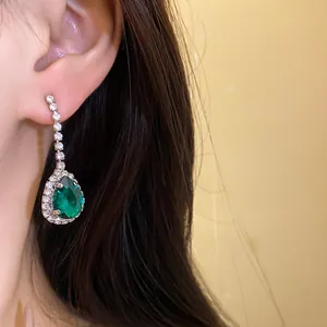 Primo piano di eleganti orecchini a goccia color smeraldo con dettagli in nappe di strass