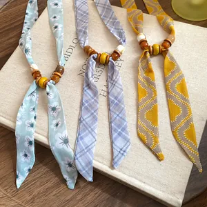 Close-up detail of three patterned fabric necklaces with wooden beads on a book