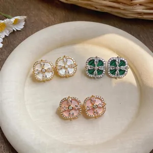 Boucles d'oreilles fleurs élégantes avec pierres colorées et zircons brillants sur plat blanc