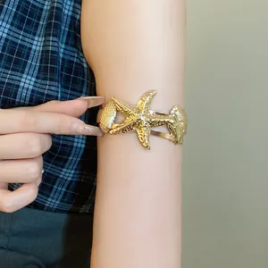 Gold starfish and seashell upper arm cuff bracelet with vintage textured finish.