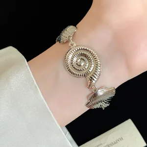Detailed view of metallic silver nautilus shell charm bracelet with shiny wrinkled texture