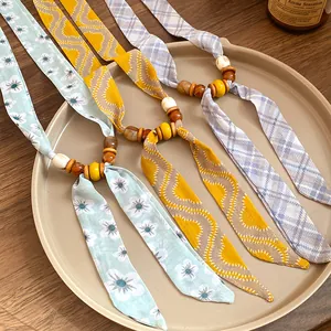Detail view showing three colorful fabric beaded necklaces in floral and plaid patterns