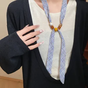 Close-up detail of a blue plaid fabric necklace with wooden beads on a black cardigan.