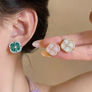 Vue macro détaillée de boucles d'oreilles fleurs en zircon vert, rose et blanc sur modèle