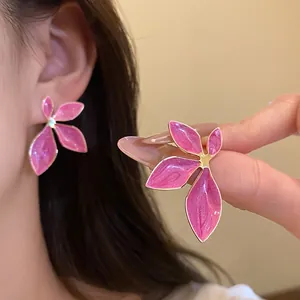 Detailed shot of elegant pink enamel flower stud earrings with gold-plated trim for women