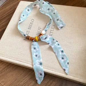 Detail of the blue floral fabric choker featuring rustic wooden and ceramic beads