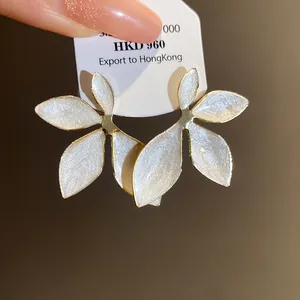 Close-up of elegant flower stud earrings with pearlescent white petals and gold finish
