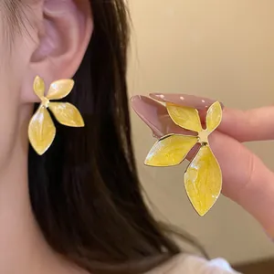 Detailed view of elegant yellow enamel flower stud earrings with a vintage golden finish.