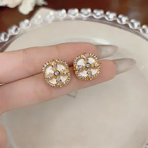 Vue détaillée de boucles d'oreilles fleurs en zircon or sur une assiette blanche.