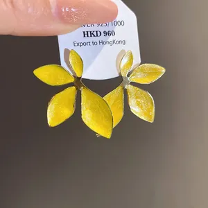 Detailed macro view of yellow enamel flower earrings on a white jewelry display card.