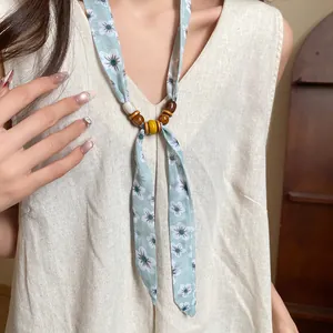 Close-up of a blue floral fabric necklace with rustic wooden and ceramic beads