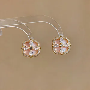 Gros plan d'élégantes boucles d'oreilles fleur dorées avec incrustation rose et zircons