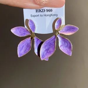 Close-up of purple enamel flower stud earrings with shimmering glitter detail