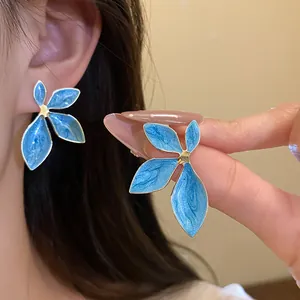 Detail view of vintage style blue enamel flower stud earrings with elegant gold accents
