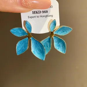 Macro detail of blue enamel flower earrings with gold trim on white display tag