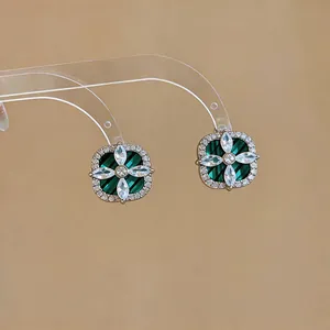 Détail macro de boucles d'oreilles fleur en zircon avec une base géométrique verte