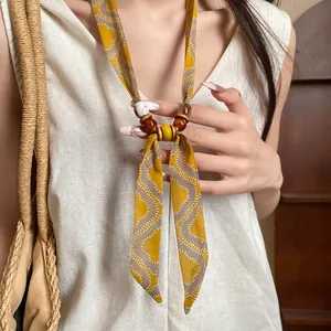 Detailed view of bohemian style fabric necklace with yellow pattern and beads